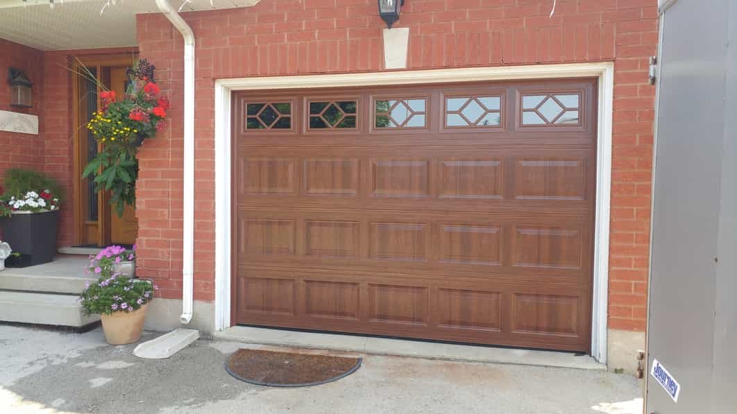 Brown garage door with windows installed on a property by Pro Entry Garage Doors